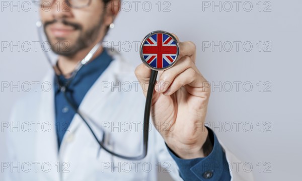 Doctor holding stethoscope with United Kingdom flag. United Kingdom health and care concept, United Kingdom flag on stethoscope