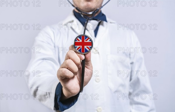 Doctor hands holding stethoscope with United Kingdom flag. United Kingdom health and care concept