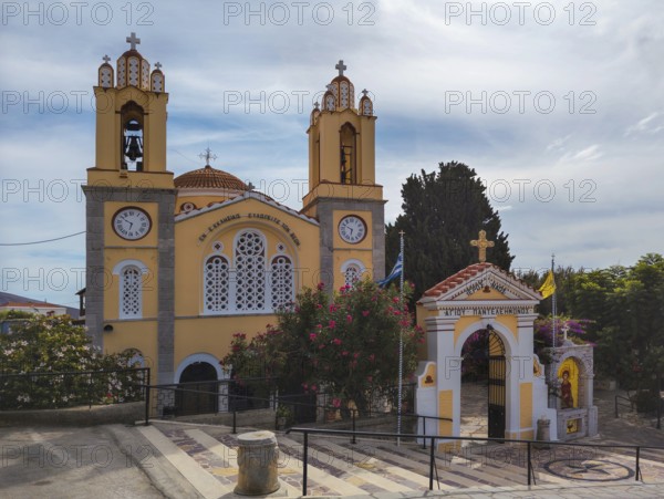 Yellow church with bell towers and flowers under a blue sky, Greek Orthodox Church of Saint Pantaleon, Siana, Rhodes Island, Greece