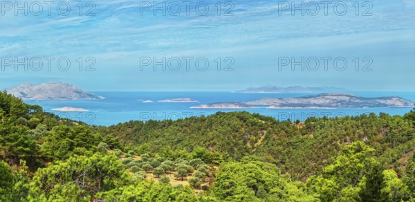 Wide view of a dense forest and the blue sea with islands Chalki and Alimia on the horizon under a clear sky, Ataviros, Rhodes Island, Greece