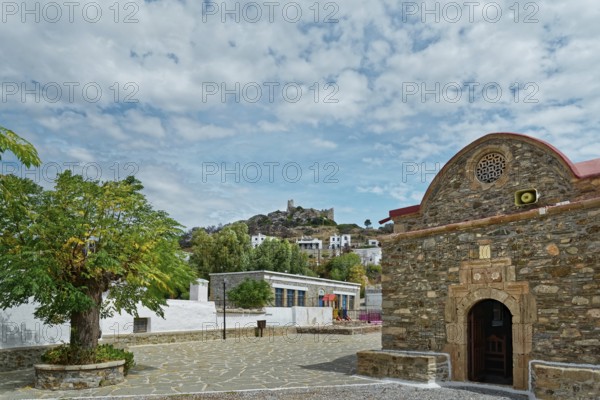 Small church Kimisis tis Theotokou made of stone with red roofs, blue sky and the castle ruins Kastro Asklipiio, Greek Orthodox Church Kimisis tis Theotokou, Asklipiio, Rhodes Island, Greece