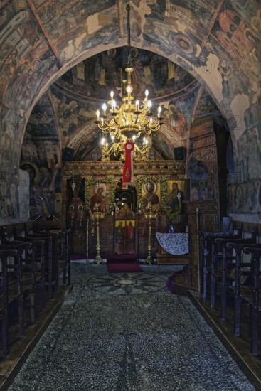 Magnificently decorated church interior with frescoes and a large candlestick that creates a spiritual atmosphere, Greek Orthodox Church Kimisis tis Theotokou, Asklipiio, Rhodes Island, Greece