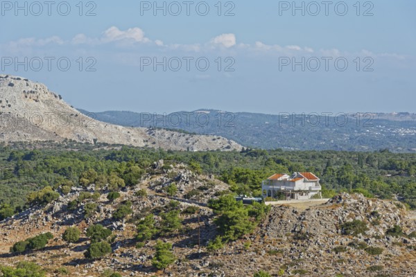 Single house on a rocky hill in the middle of a barren and lush landscape, Archangelos, Rhodes Island, Greece