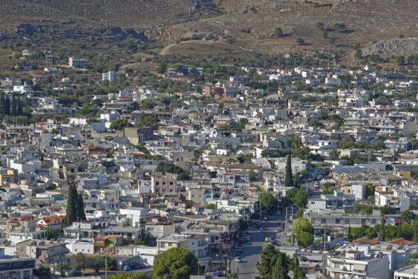 Town of Archangelos with densely built blocks of houses and green trees on hilly terrain, Archangelos, Rhodes Island, Greece