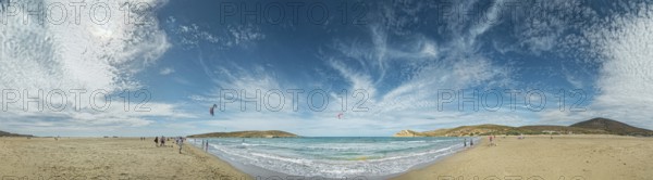 Beach panorama of Prasonisi with light sand, blue sea and two kite surfers under a cloudy sky, Prasonisi, Rhodes Island, Greece