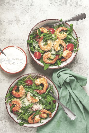 Two bowls of shrimp salad, arugula and cherry tomatoes, with parmesan cheese, healthy food