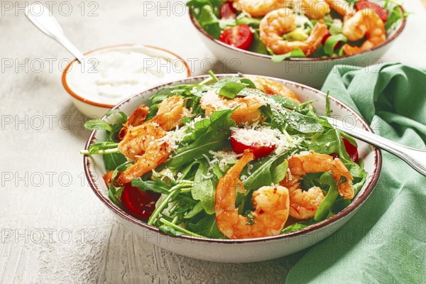 Two bowls of shrimp salad, arugula and cherry tomatoes, with parmesan cheese, healthy food
