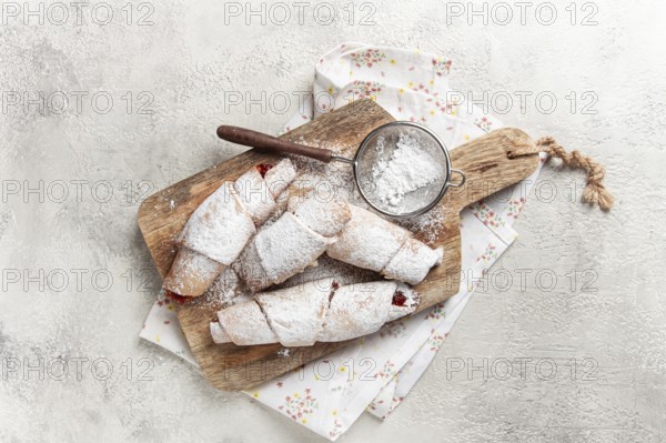 Bagels with filling, sweet pastries, sprinkled with powdered sugar, on a wooden board, dessert, breakfast
