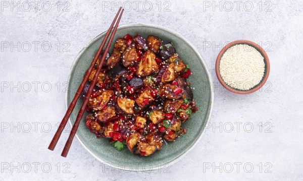Fried eggplant, Chinese style, in sweet and sour sauce, with pepper and sesame seeds, in a green bowl