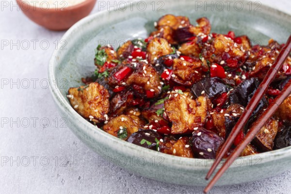 Fried eggplant, Chinese style, in sweet and sour sauce, with pepper and sesame seeds, in a green bowl