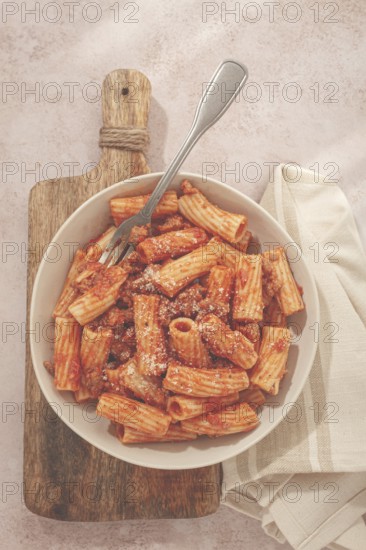 Rigatoni pasta with meat sauce and parmesan cheese on a light table, top view, homemade, no people