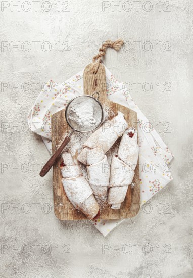 Bagels with filling, sweet pastries, sprinkled with powdered sugar, on a wooden board, dessert, breakfast