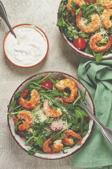 Two bowls of shrimp salad, arugula and cherry tomatoes, with parmesan cheese, healthy food