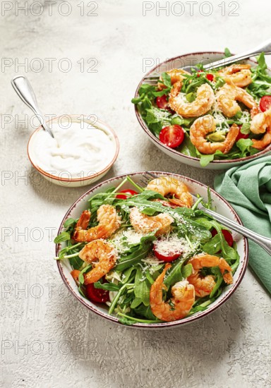 Two bowls of shrimp salad, arugula and cherry tomatoes, with parmesan cheese, healthy food