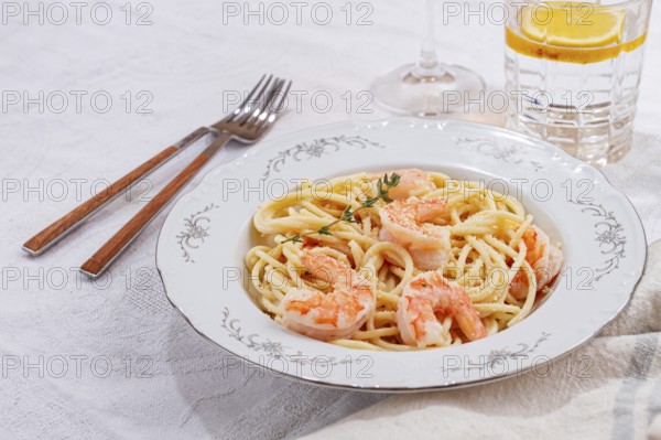 Pasta with shrimp and thyme, served on a white plate, with a glass of white wine, the table is set, Gourmet dinner, on a linen tablecloth, no people