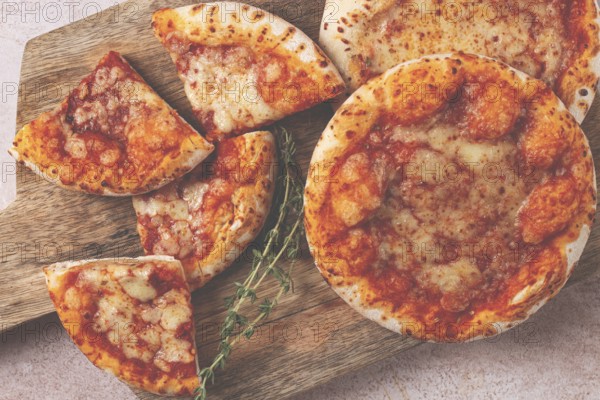 Four pizzetta Margaritas, on a cutting board, on a light gray surface, top view