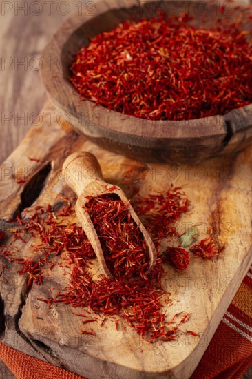 Spice saffron threads, in a wooden bowl, on a wooden table, top view, close-up