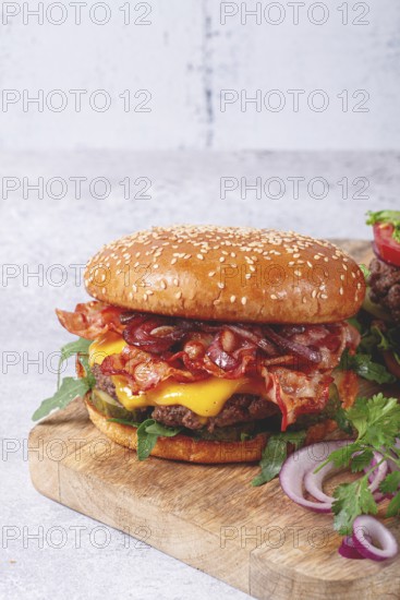 Burger with beef and bacon, with arugula and caramelized onions, pickles, sauce, homemade, no people