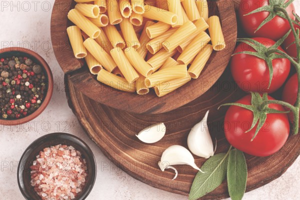 Pasta ingredients spread out, on a wooden surface, with tomatoes and spices, ready to cook, there are no people