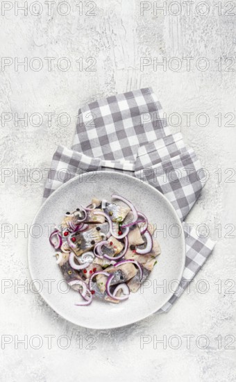 Salted herring, with spices and red onion, sliced fillet, on a plate, top view