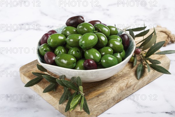 Chalkidiki olives, classic Greek green olives, in a bowl on a cutting board, top view, without people