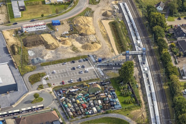 Aerial view, Friedrichsfeld (Niederrhein) railway station, construction site with new building and stairway to the platform with pedestrian bridge, car park and bicycle stand, scrap yard with old military trucks at Friedrichsfeld railway station, Friedrichsfeld, Voerde, Ruhr area, North Rhine-Westphalia, Germany, railway area, railway station, railway platform, DE, Deutsche Bahn AG, Europe, railway tracks, tracks, aerial view, aerial photography, aerial photography, Lower Rhine, scrap yard, overview, Voerde (Lower Rhine), bird's-eye view, recycling, birds-eyes view, overview