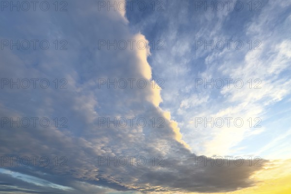 Cloud front with grey stratocumulus below right left and bright altocumulus clouds above Altocumulus clouds Cluster layer clouds under blue sky Evening sky shortly in front of dusk over treetops of forest edge of mixed forest, international