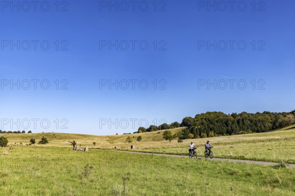 Pristine landscape in the Swabian Alb biosphere reserve with blue skies and cyclists. The former military training area in Münsingen is an important part of the 85, 270-hectare nature reserve. It was established by the state of Baden-Württemberg in 2008. It has been a UNESCO biosphere reserve since 2009. Münsingen, Baden-Württemberg, Germany