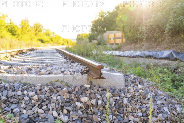 Railway tracks surrounded by plants at sunset, Hermann Hessebahn construction site, Calw, Germany