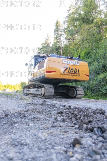 A large excavator on a construction site with trees in the background, Hermann Hessebahn construction site, Calw, Germany