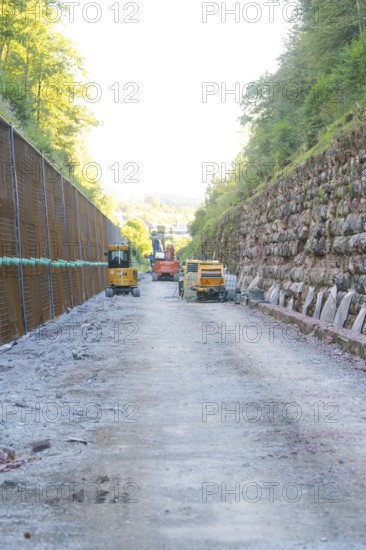 Construction site with heavy machinery on a stony road between steep embankments, Hermann Hessebahn construction site, Calw, Germany