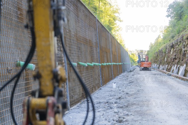 View along a construction wall with construction site vehicles and equipment, Hermann Hessebahn construction site, Calw, Germany