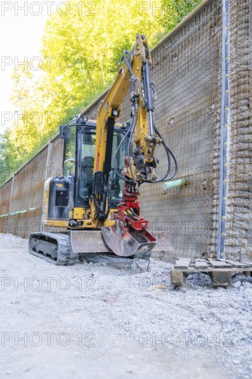 Mini excavator next to a metal mesh construction wall on a building site, Hermann Hessebahn construction site, Calw, Germany