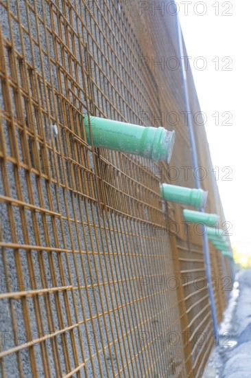 Side view of a construction wall with metal mesh and pipework, Hermann Hessebahn construction site, Calw, Germany