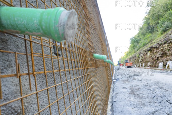 Close-up of a construction wall with metal mesh and green pipes, Hermann Hessebahn construction site, Calw, Germany