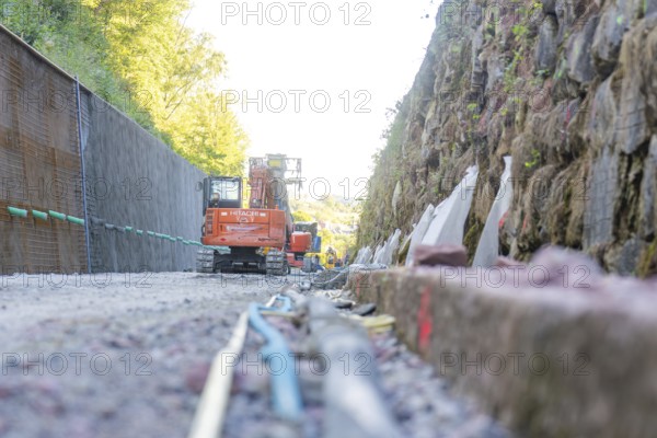 Excavator on a rock wall at an outdoor construction site, Hermann Hessebahn construction site, Calw, Germany
