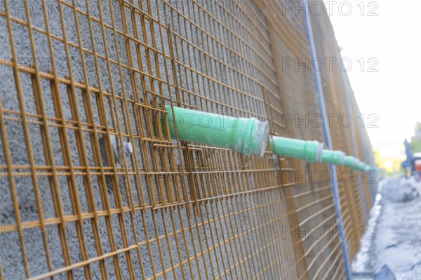 Metal grid with green pipes in front of a concrete wall on a construction site, Hermann Hessebahn construction site, Calw, Germany