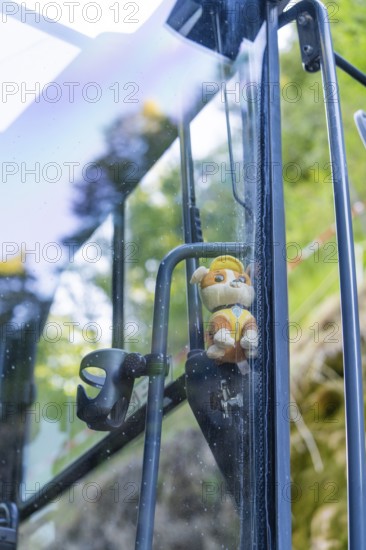 Toy figure with helmet behind a glass pane with nature in the background, Hermann Hessebahn construction site, Calw, Germany