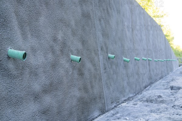 A row of green pipes protrudes from a reinforced concrete wall on a construction site, Hermann Hessebahn construction site, Calw, Germany