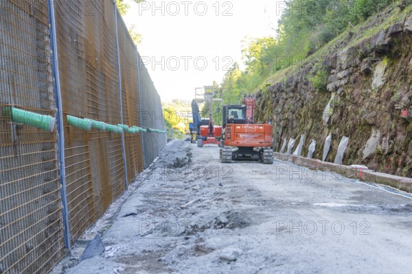 Construction site with excavator and stacked concrete material outdoors, Hermann Hessebahn construction site, Calw, Germany
