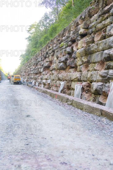 Robust stone walls along a gravel road in a wooded area, Hermann Hessebahn construction site, Calw, Germany
