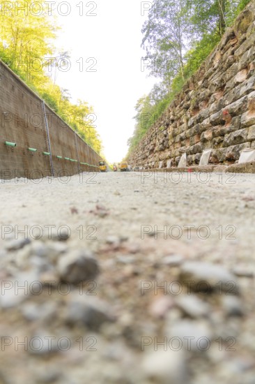 A gravel road with high walls on both sides in a wooded area, Hermann Hessebahn construction site, Calw, Germany