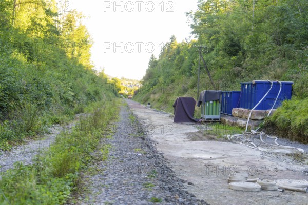 Gravel path with containers and cables in a wooded area along the track, Hermann Hessebahn construction site, Calw, Germany
