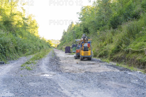 Construction machinery on a busy gravel road, surrounded by wooded slopes, Hermann Hessebahn construction site, Calw, Germany