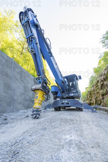 Blue crane with drill head on construction site on concrete wall, surrounded by nature, Hermann Hessebahn construction site, Calw, Germany