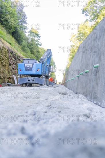 Blue excavator on a dusty road between two walls, Hermann Hessebahn construction site, Calw, Germany