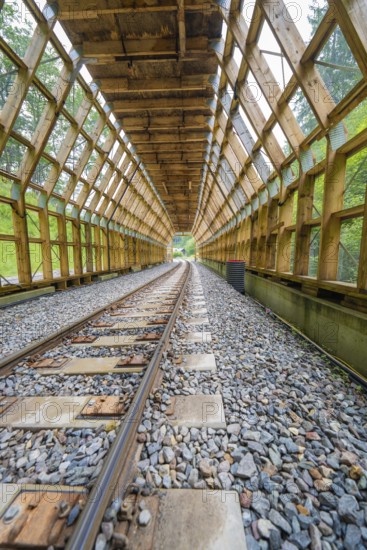 Open wooden tunnel with a view of daylight through wooden structures, construction of the Hermann Hesse railway, Calw, Black Forest, Germany