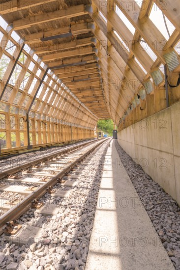 Wooden tunnel structure over railway tracks, bright sunlight floods the room, construction of the Hermann Hesse railway, Calw, Black Forest, Germany