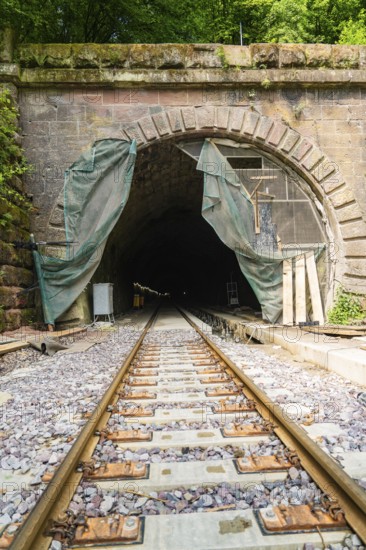 Railway tunnel with rails and stone wall, surrounded by green plants, renovation work in progress, construction of the Hermann Hesse railway, Calw, Black Forest, Germany