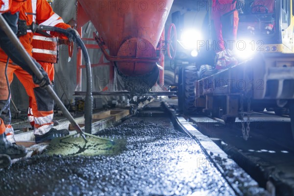 Construction workers pouring concrete under strong lighting, industrial atmosphere and safety equipment, construction of the Hermann Hesse railway, Calw, Black Forest, Germany